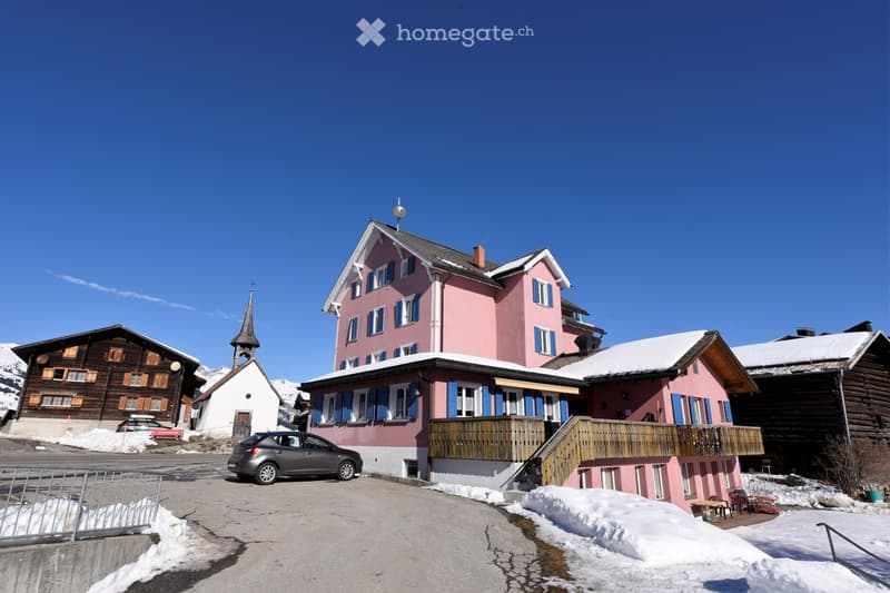 pink house, wooden balcony, snow on the roof, car parked in front