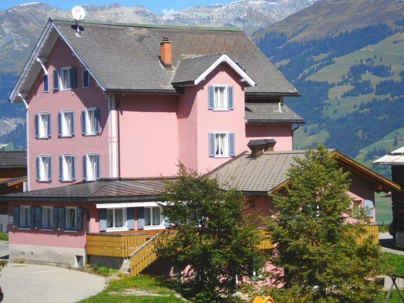 pink house, gray roof, wooden balcony, chimney, satellite dish, mountain view