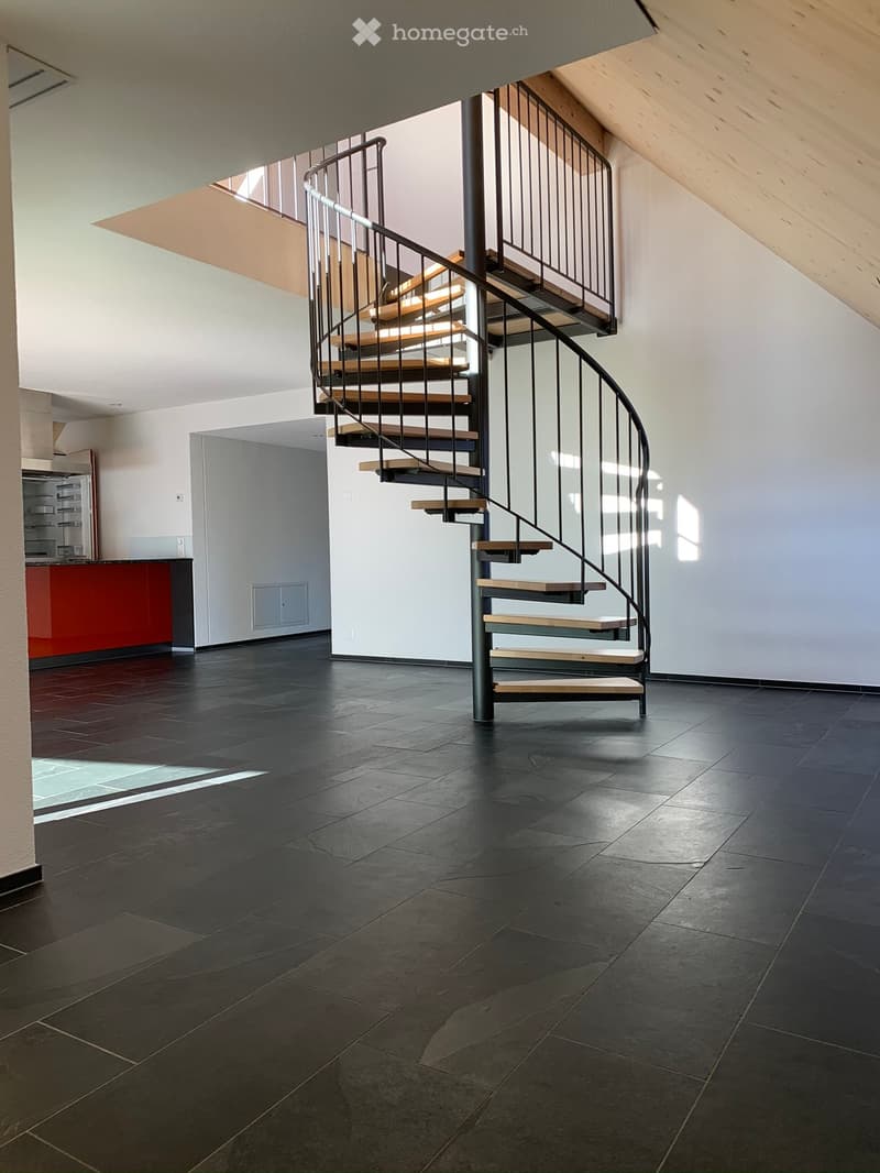 Open floor plan, spiral staircase, black tiled floor, white walls, red kitchen counter