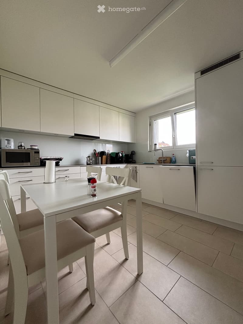 modern kitchen with white cabinets, white table and chairs, tiled floor, microwave, coffee machine, dishwasher, sink, refrigerator