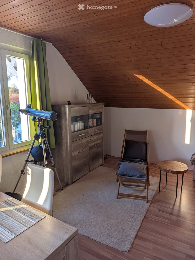 A room with a telescope, a wooden cabinet, a white chair, a wooden lounge chair, a wooden table, and a carpet.