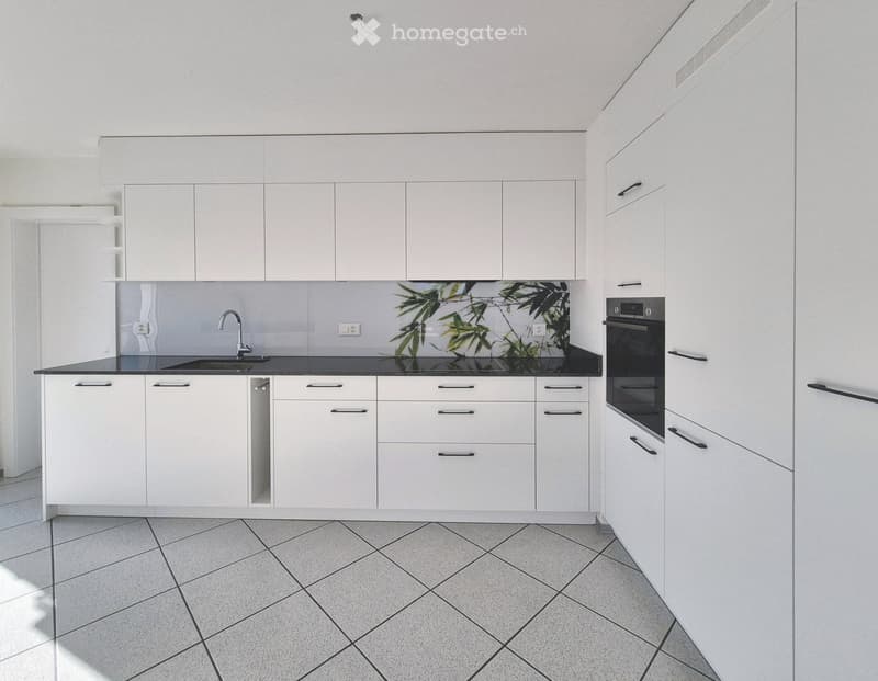Kitchen. Modern kitchen with white cabinets, black countertops, and a tiled floor. Features a sink with a modern faucet and an oven.