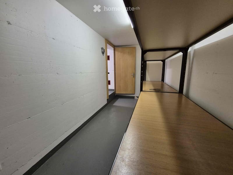 Empty hallway with white walls, wooden floor, and a door at the end.