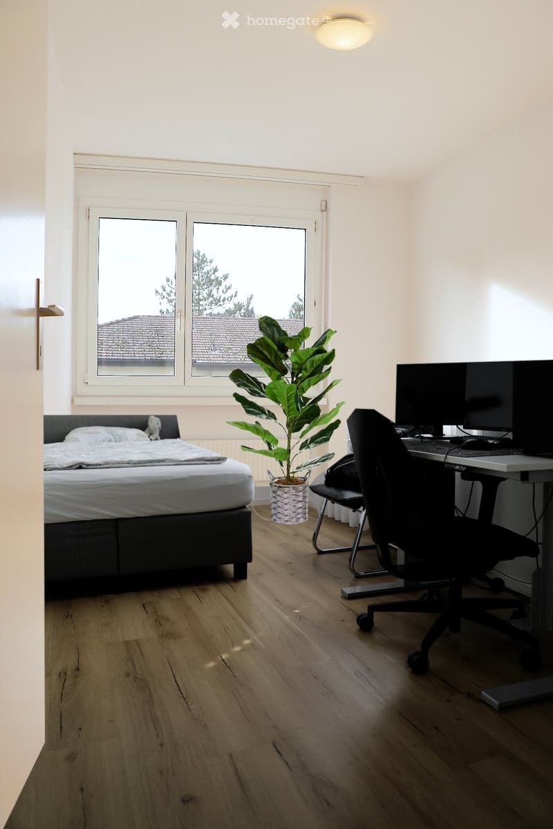 bedroom with bed, desk, chair, plant, window, radiator