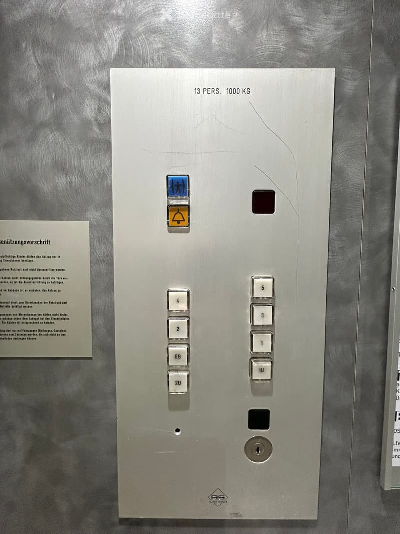 Elevator control panel with buttons for floors 1 to 5, emergency stop button, and a weight limit of 13 persons and 1000 kg.