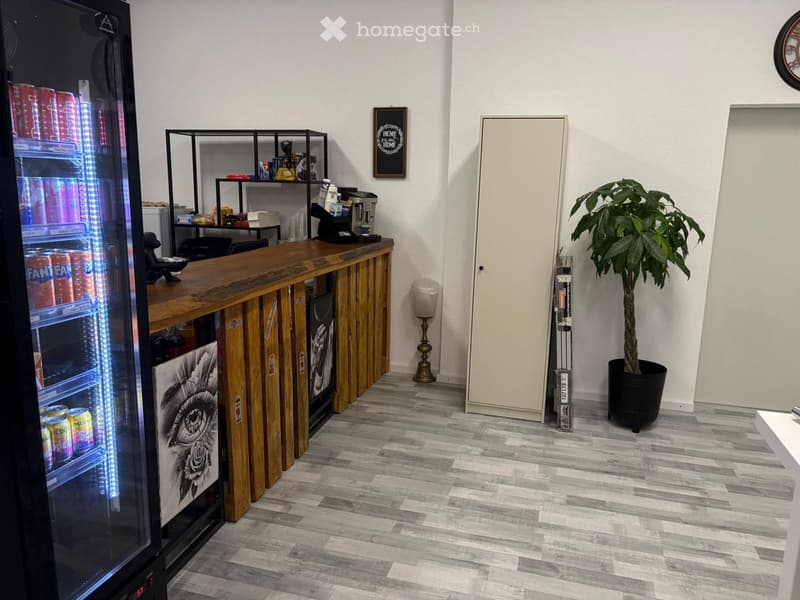 Counter with fridge, shelves, coffee machine, plant, cabinet, trash bin, lamp, picture frame, clock