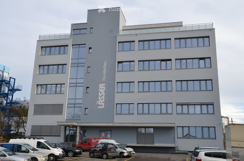 modern office building, grey exterior, large windows, multiple floors, parking lot in front