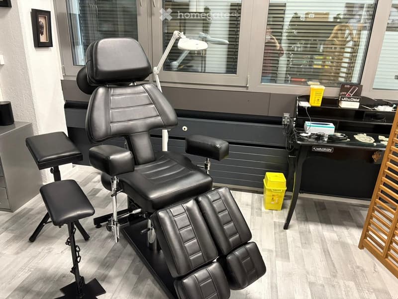 black leather chair, footrest, lamp, desk, yellow bins, window with blinds