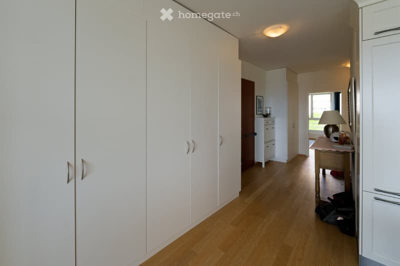 wooden floor, white wardrobes, white cabinets, table with lamp, picture frame, window