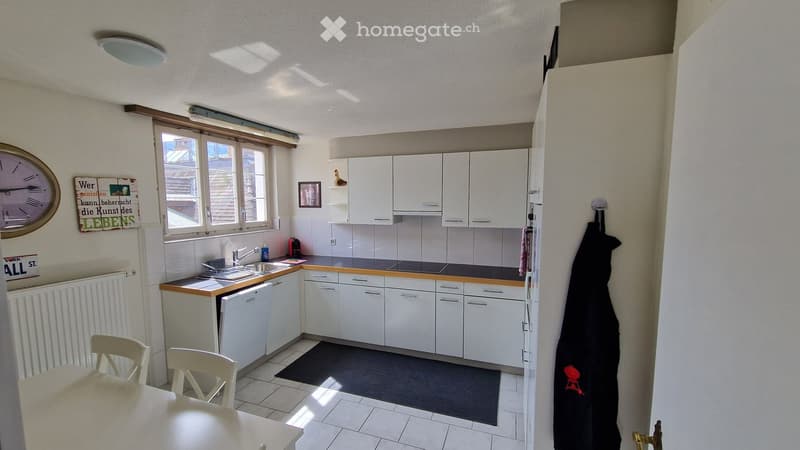 modern kitchen with white cabinets, black tiled floor, dishwasher, washing machine, window, radiator, clock, framed picture, black rug