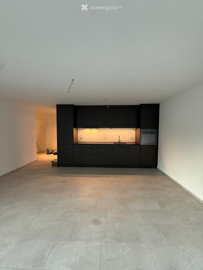 Empty kitchen with black cabinets, granite countertops, and tiled floor.