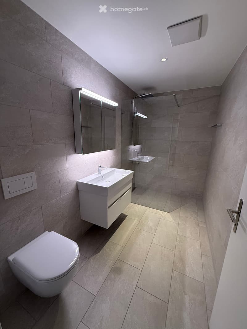 modern bathroom with white tiles, white toilet, white sink, glass shower enclosure, mirror