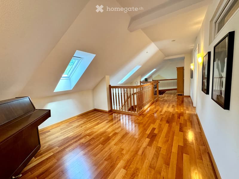 large room with wooden flooring, wall-mounted pictures, piano, open attic space, loft
