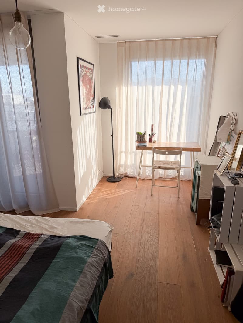 bedroom with bed, desk, chair, lamp, picture frame, curtains, wooden floor