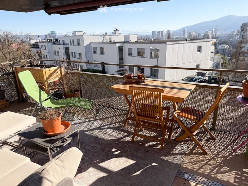 Balcony with table, chairs, lounge chair, potted plants, and a view of the city