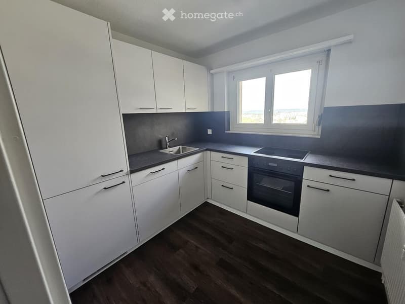 modern kitchen with white cabinets, black countertops, stainless steel sink, oven, and window