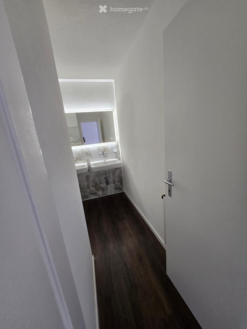 Bathroom with two sinks, mirror, wooden floor, white walls