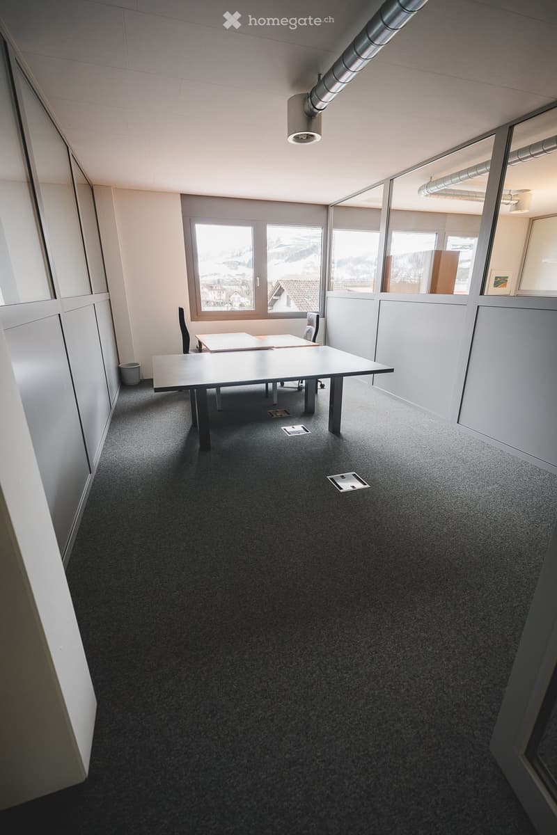 empty room, two tables, two chairs, carpeted floor, glass walls, windows