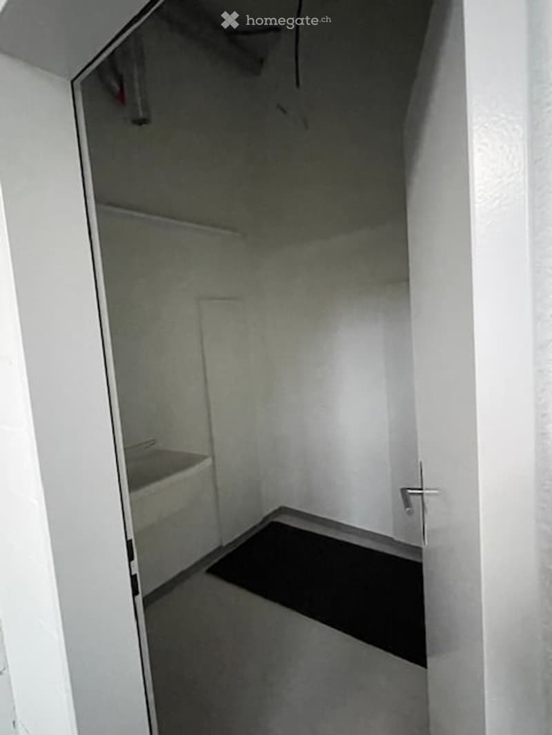 empty room, white walls, white sink, black mat on the floor