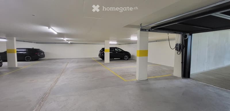 underground parking lot with two cars parked, yellow lines, white ceiling, white walls, pillars