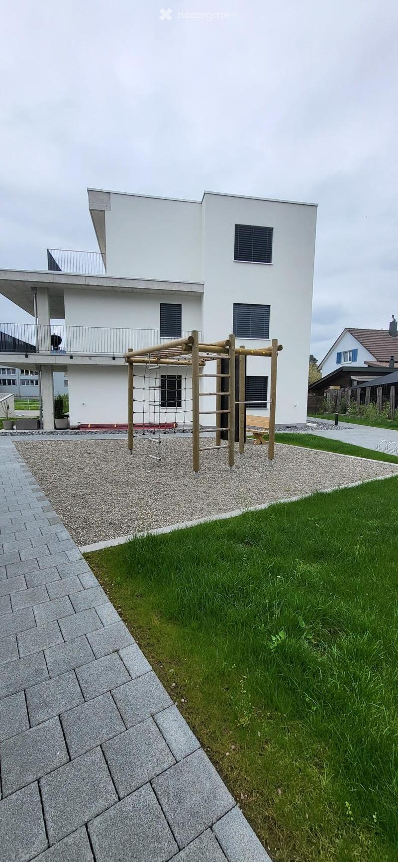modern white house, 2 stories, balcony, gravel path, wooden play structure, green lawn