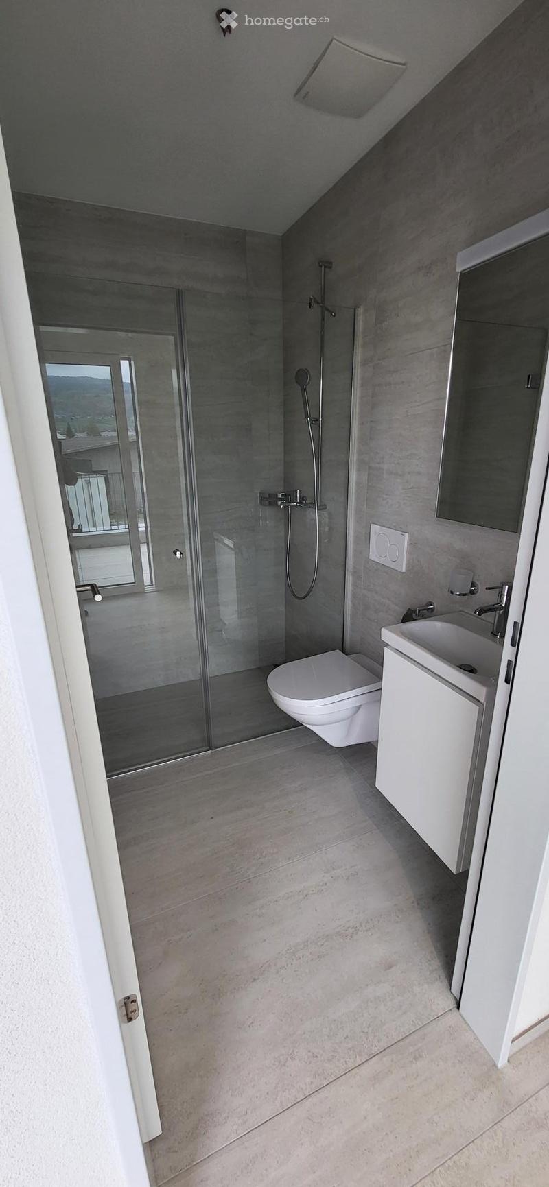 modern bathroom with glass shower, white toilet, white sink, mirror, white cabinet, tiled floor