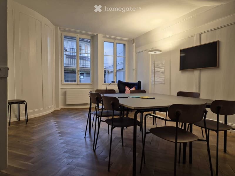 conference room, long table, chairs, windows, radiator, mounted TV, floor lamp