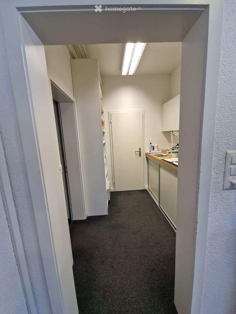 Empty room with white walls, gray carpet, white cabinets, and a white door.