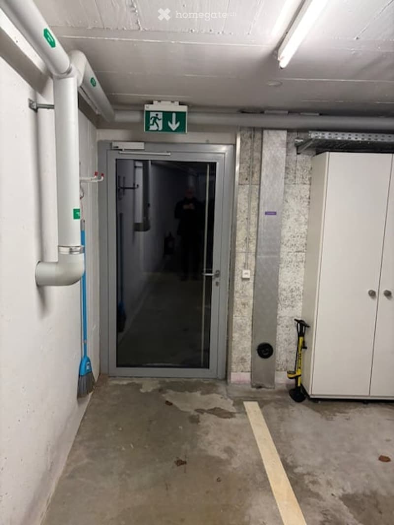 Entrance to a garage with a glass door, a white cabinet, and a broom