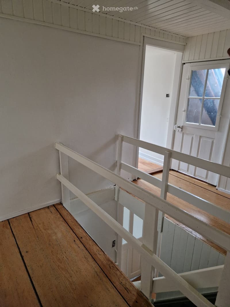 white walls, wooden floor, white railings, white doors, small window