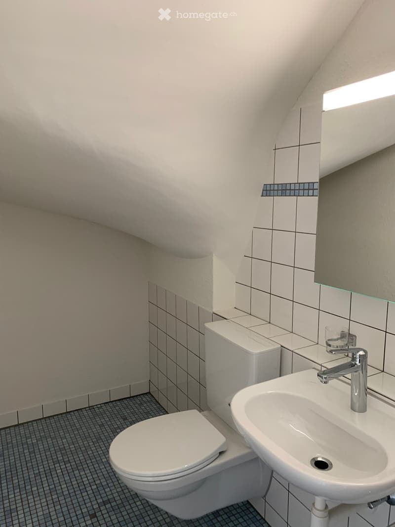 Bathroom with white tiles, white toilet, white sink, silver faucet, mirror, and ceiling light