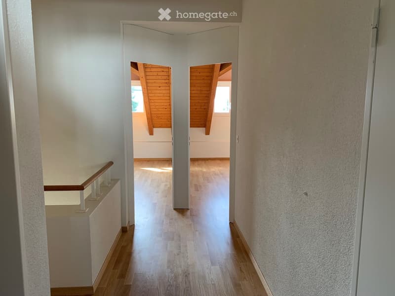 Empty hallway with wooden floor, white walls, wooden ceiling, two doors, and two windows