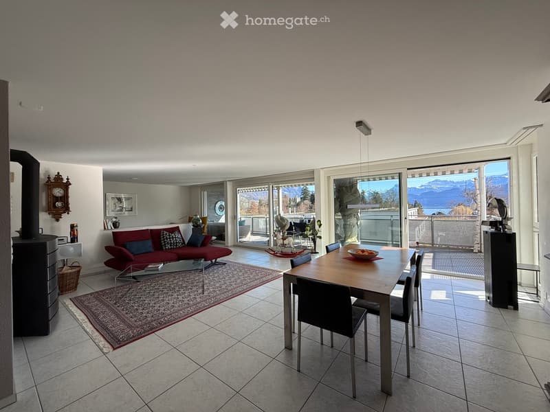 open-plan living room and dining area, balcony, glass table, red couch, tiled floor, wooden dining table, view of mountains