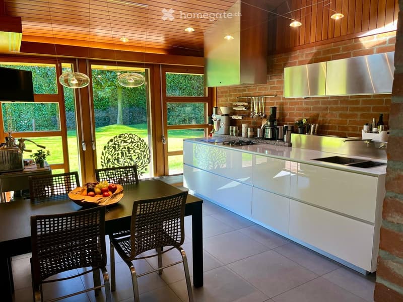 modern kitchen, white cabinets, black table, kitchen island with 2 sinks, brick wall, glass doors