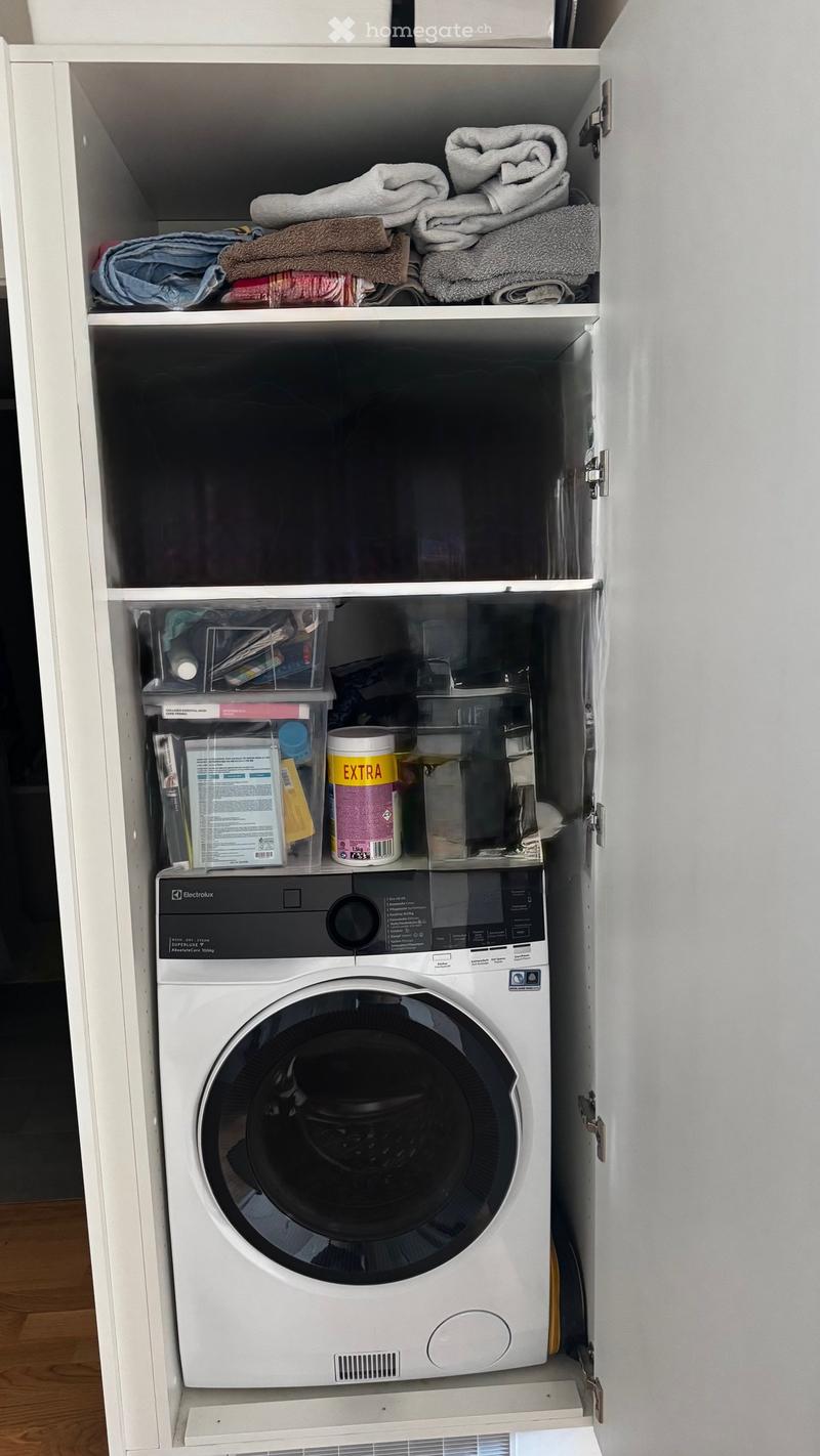 A white cabinet with shelves, a washing machine, and various items on the shelves.