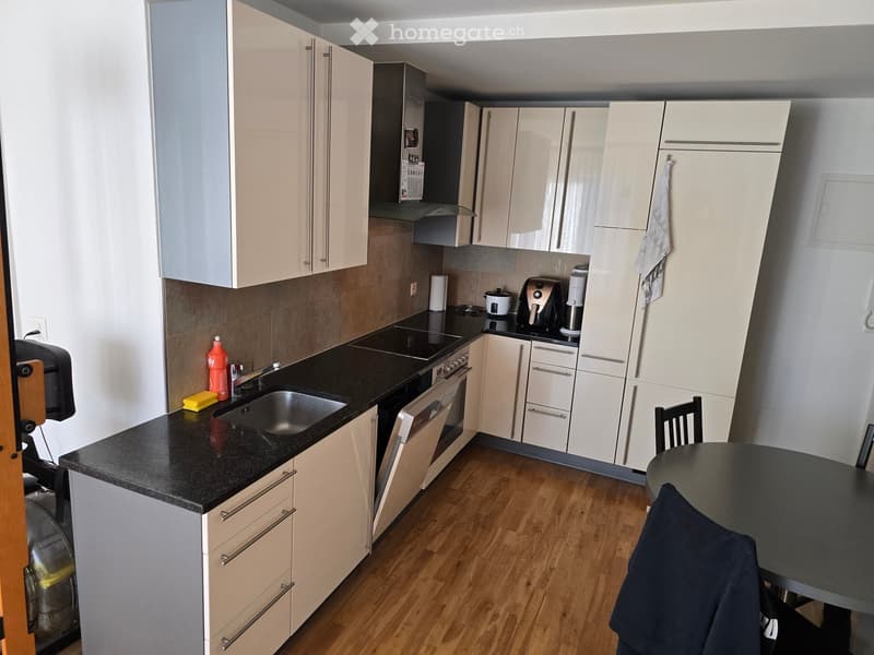 modern kitchen with white cabinets, black countertops, stainless steel appliances, wooden floor