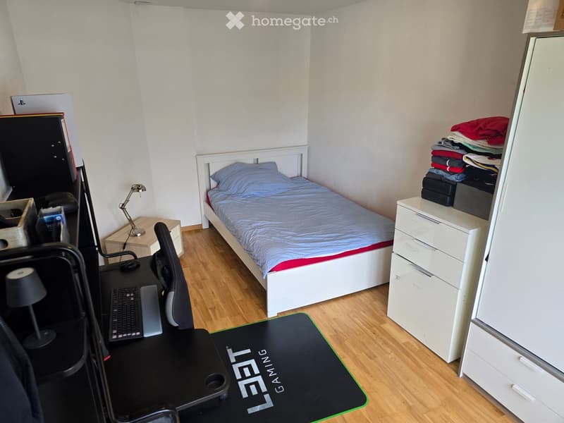 Single bed, desk, chair, lamp, keyboard, mouse, gaming mousepad, cabinet, stack of clothes