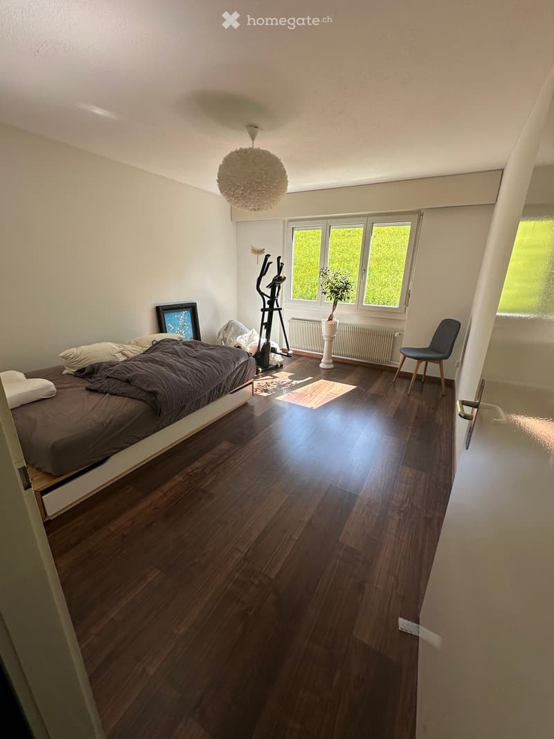 bedroom with bed, exercise equipment, window, plant, chair, radiator, wooden floor