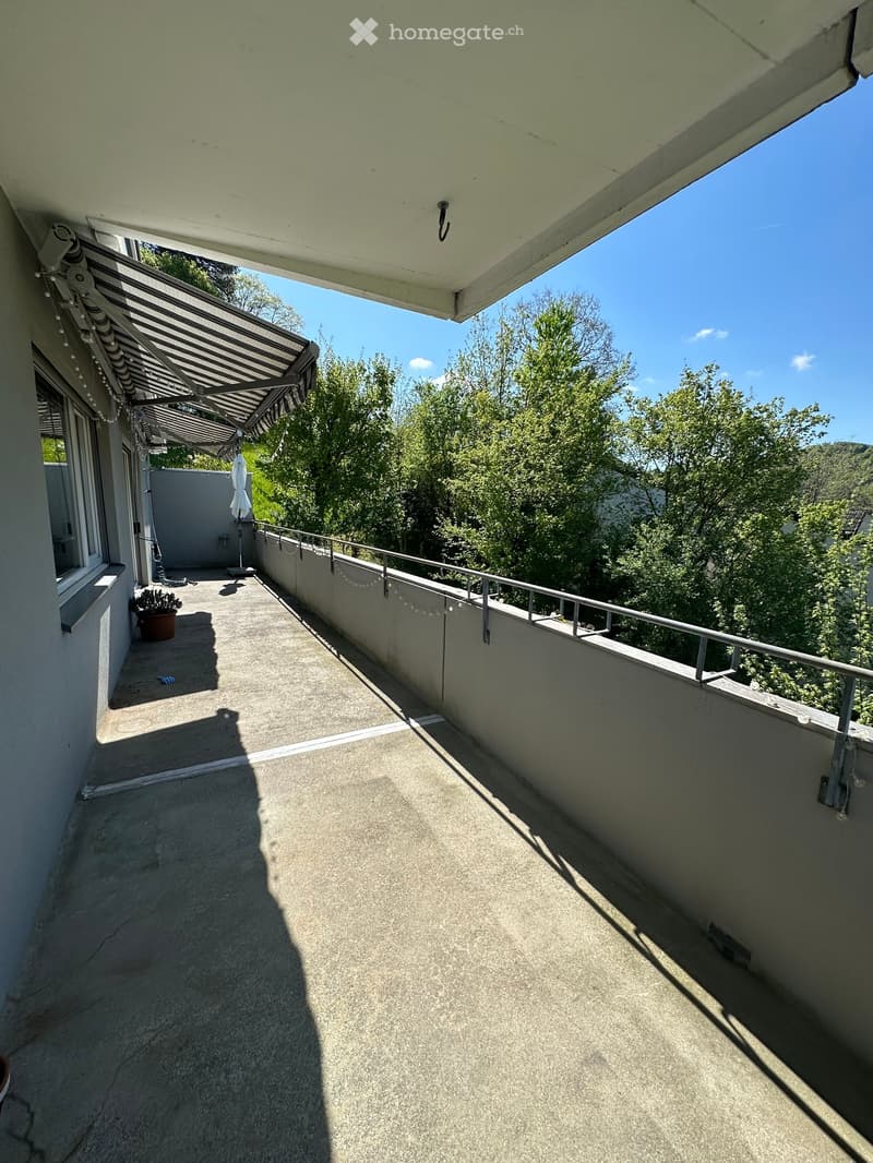 Balcony with metal railings, awning, potted plant, and a view of trees and mountains