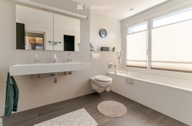modern bathroom with white sink, mirror, toilet, bathtub, and shower