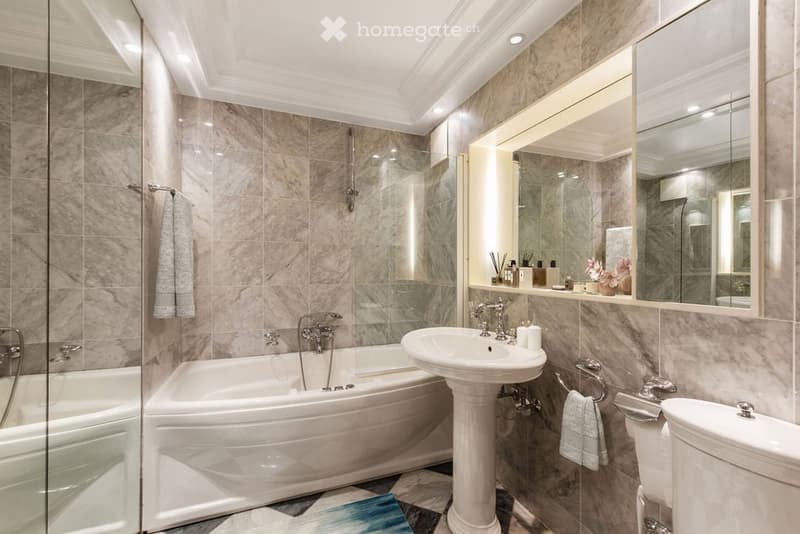 Bathroom with marble tiles, bathtub, shower, sink, toilet, and mirrors