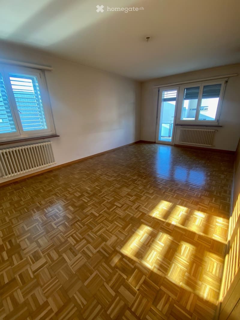 empty room, wooden parquet floor, white walls, two windows, two radiators, sliding glass door to balcony
