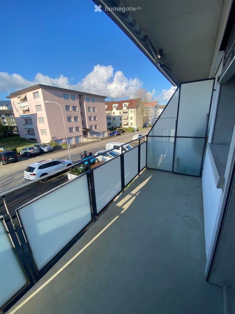 Balcony with glass railings, view of the street and parked cars