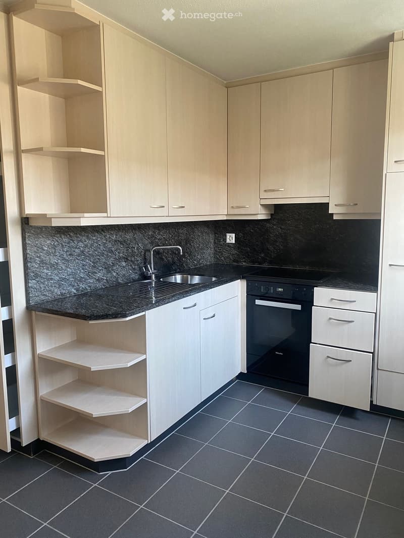 modern kitchen with white cabinets, black granite countertops, stainless steel sink, black oven, tiled floor