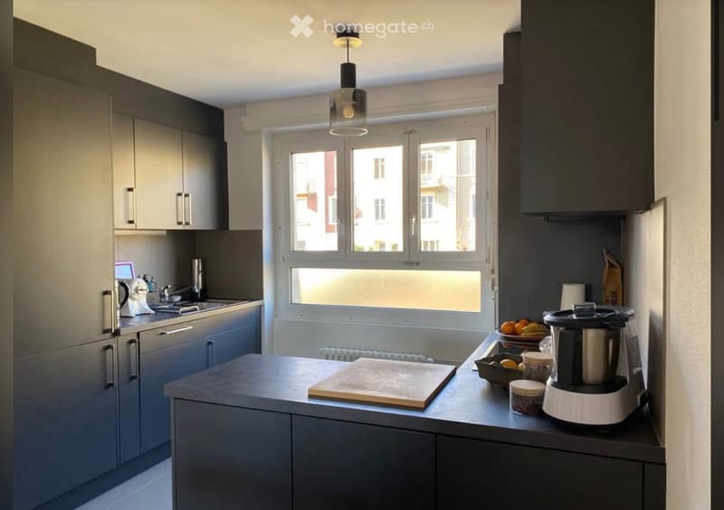modern kitchen with black cabinets, white countertops, large window, modern appliances