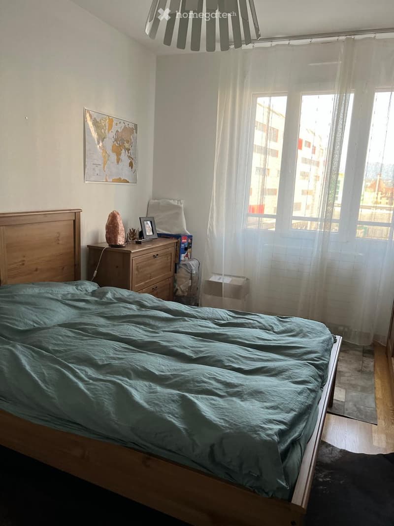 bedroom with bed, wooden cabinet, window with curtains, map on the wall