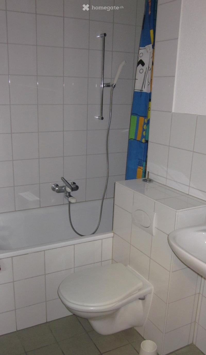 Bathroom with a toilet, bathtub, sink, shower curtain and shower head