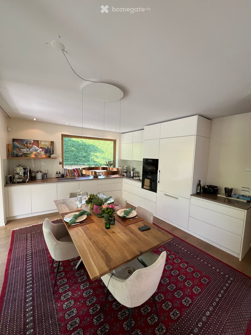 modern kitchen with dining area, wooden table, white cabinets, large window, red rug, modern lighting
