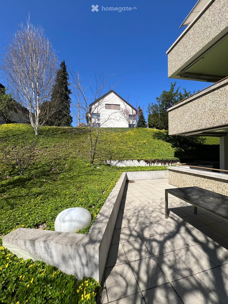 concrete walkway, green grass, white sculpture, concrete bench, shadow