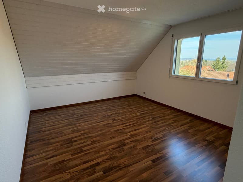 empty room, wooden floor, white walls, slanted ceiling, window with view